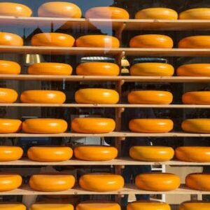 Brightly colored cheese wheels arranged on shelves behind a glass window, creating a vibrant display.